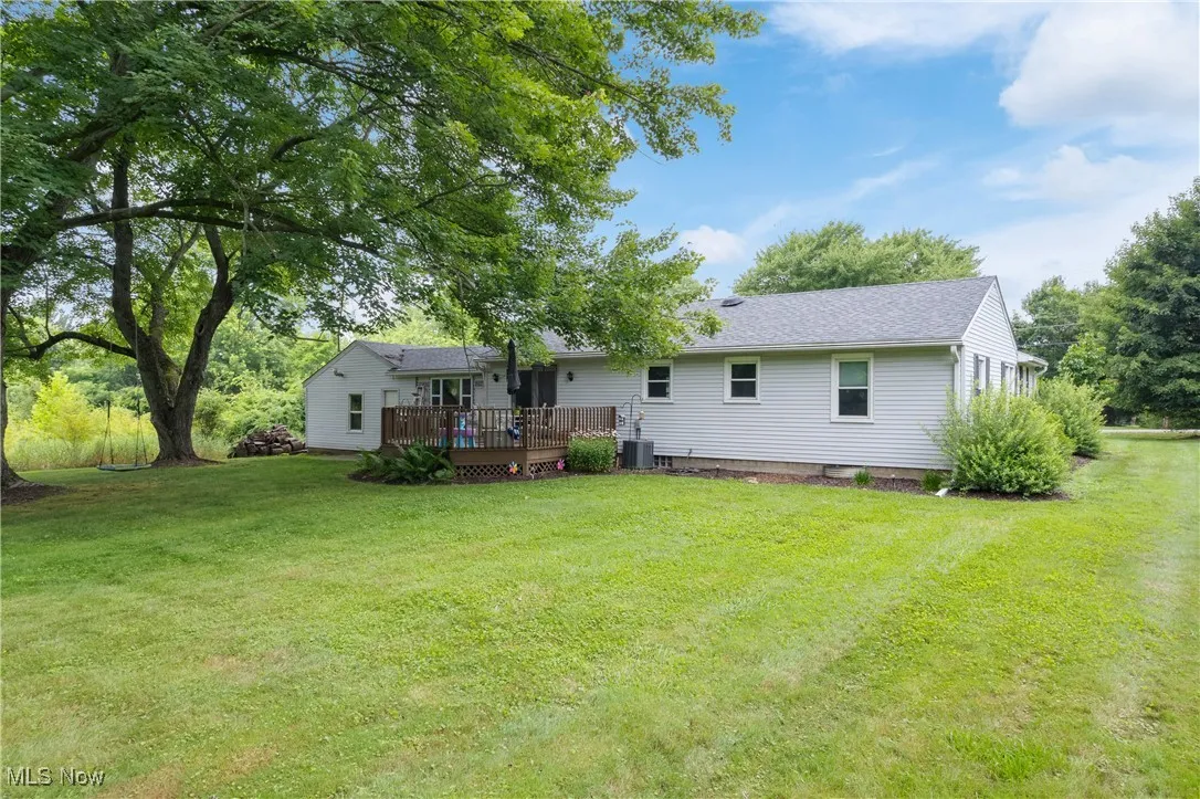 Back of house featuring a wooden deck, a yard, and a shingled roof