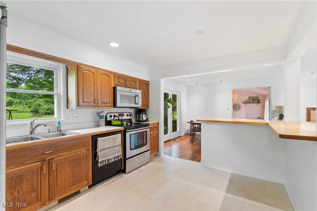 Kitchen featuring appliances with stainless steel finishes, light countertops, brown cabinets, and recessed lighting