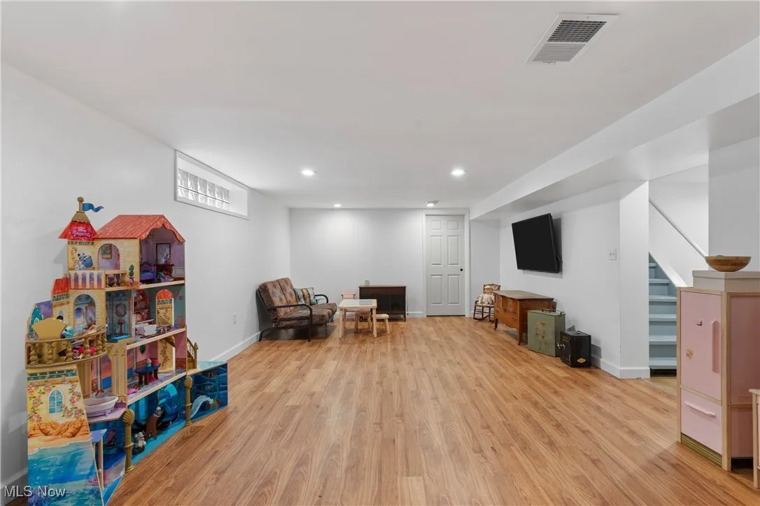 Sitting room with light wood-type flooring, recessed lighting, and stairs