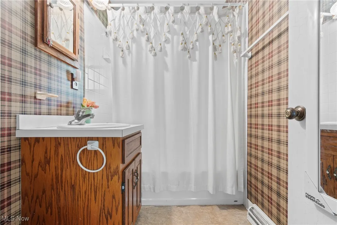 Full bath featuring wallpapered walls, vanity, shower / bathtub combination with curtain, and tile patterned flooring