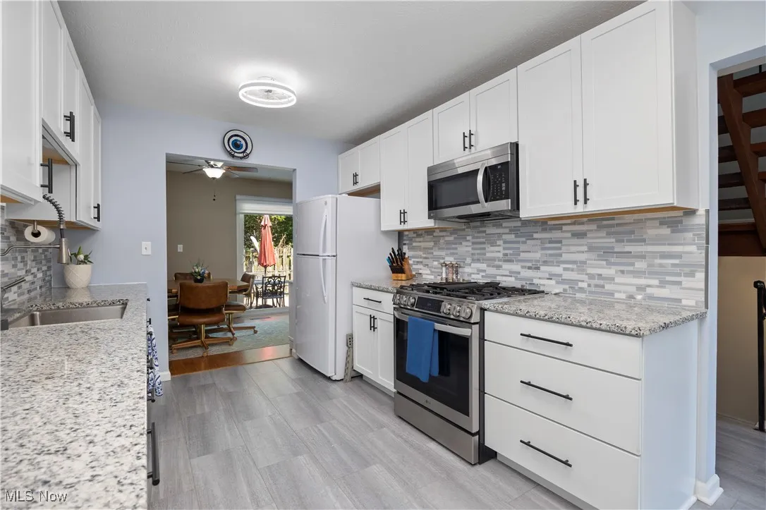 Kitchen with appliances with stainless steel finishes, ceiling fan, backsplash, and white cabinetry