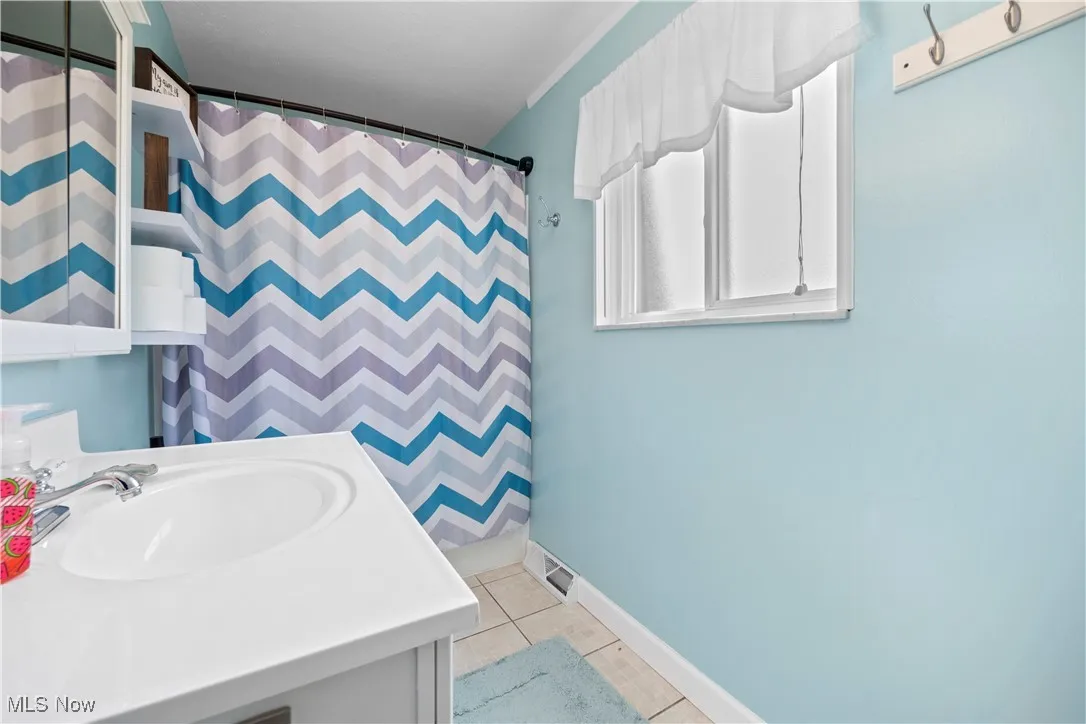 Bathroom featuring vanity, tile patterned flooring, and a shower with shower curtain