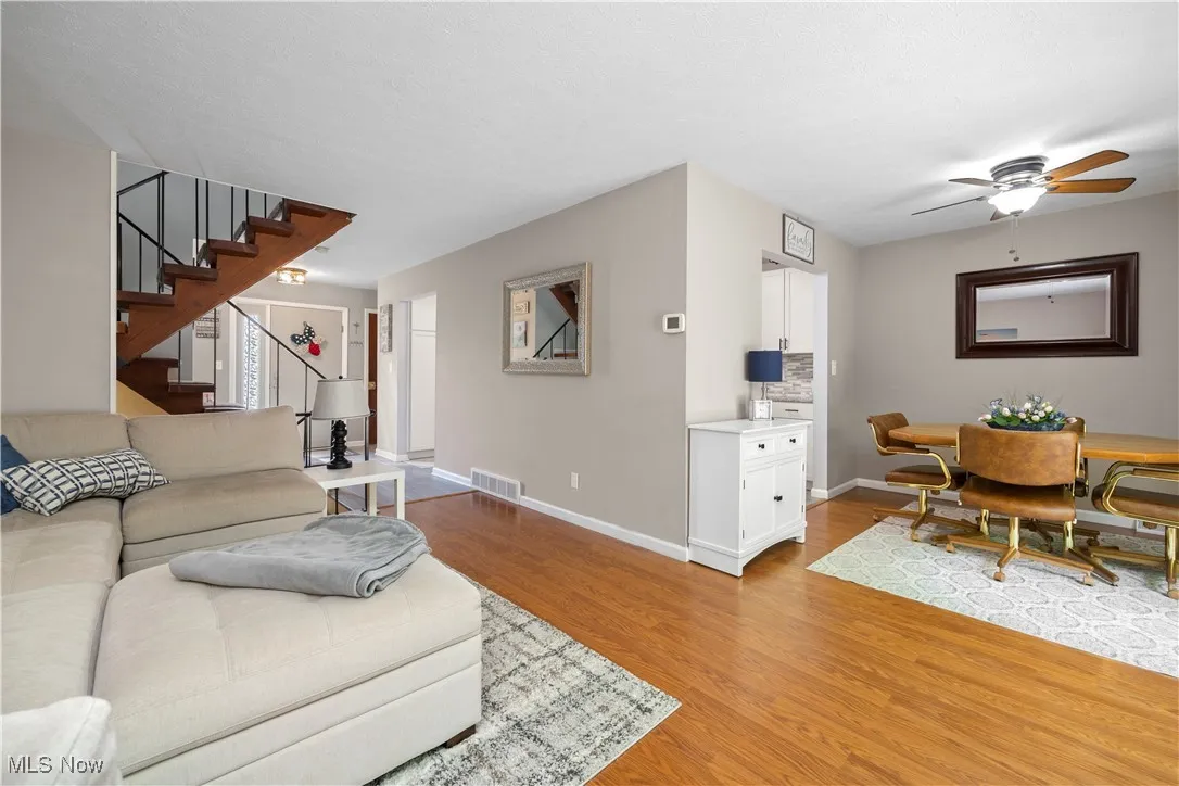 Living area with stairs, light wood-style flooring, and a ceiling fan