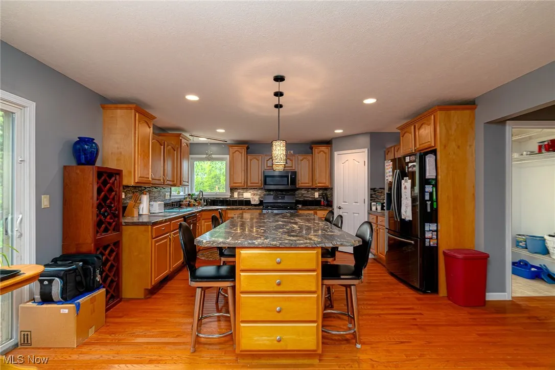 Kitchen featuring stainless steel appliances, a breakfast bar, light wood finished floors, backsplash, and recessed lighting