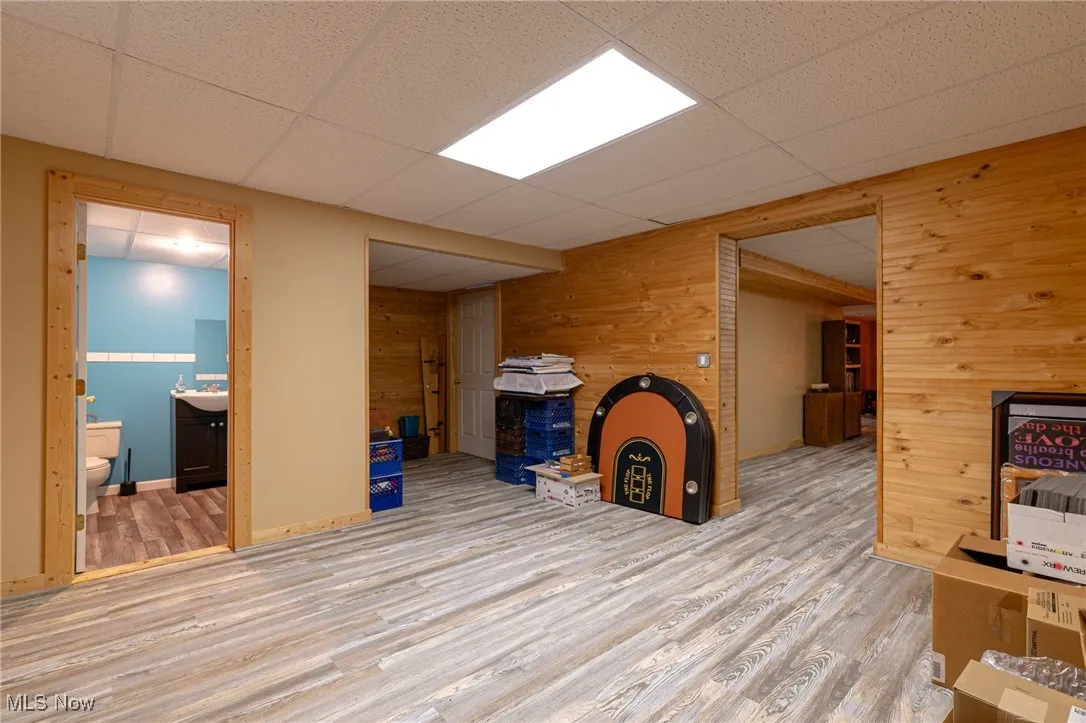 Unfurnished living room featuring wooden walls, wood finished floors, and a drop ceiling