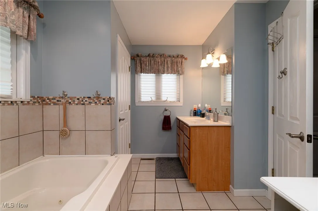 Bathroom with vanity, a whirlpool tub, and tile patterned flooring