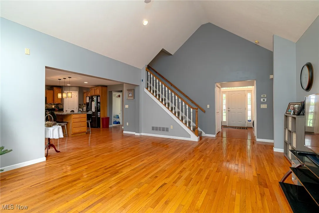Living area featuring stairs, high vaulted ceiling, and light wood-style floors