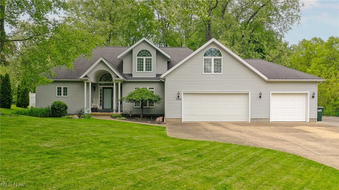 Traditional-style home featuring concrete driveway, a front yard, a shingled roof, and an attached garage