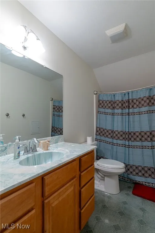 Full bathroom with vanity, lofted ceiling, and tile patterned flooring