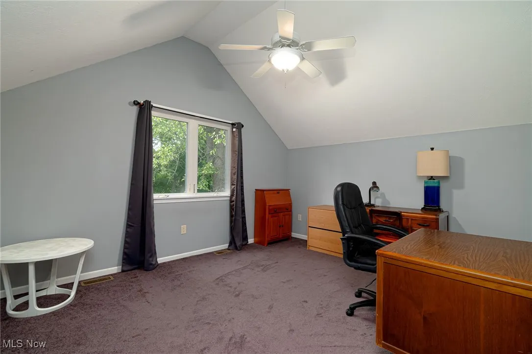 Carpeted home office with vaulted ceiling and a ceiling fan