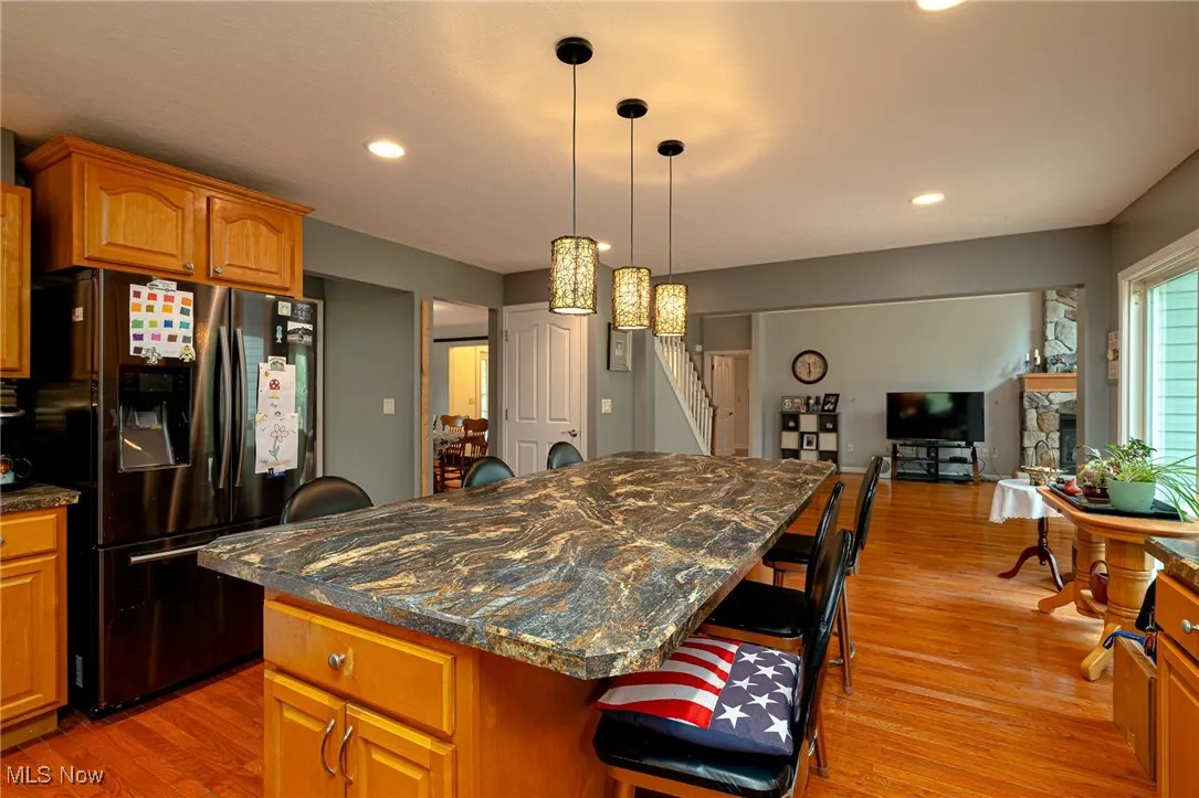 Kitchen featuring fridge with ice dispenser, a breakfast bar area, light wood-style flooring, a kitchen island, and recessed lighting