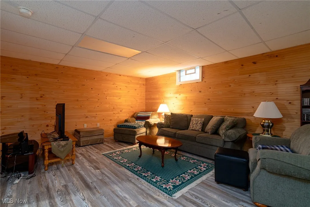 Living room with wood walls, a paneled ceiling, and wood finished floors