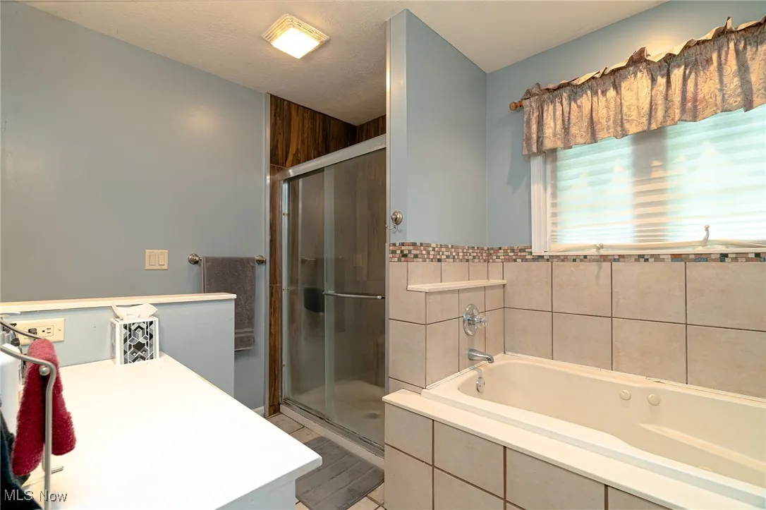 Bathroom with vanity, a garden tub, and a stall shower