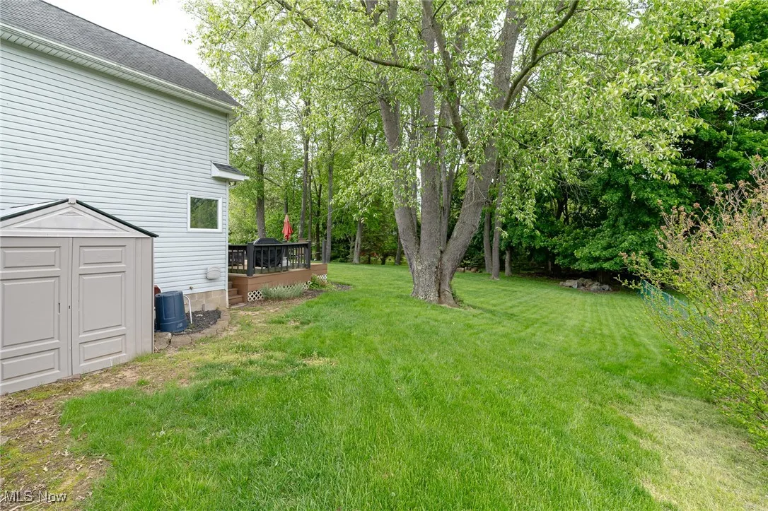 View of grassy yard featuring a storage shed and a wooden deck