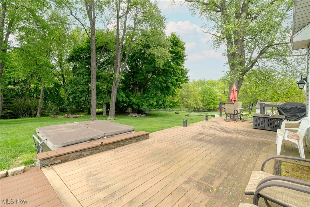 Deck with a yard, view of wooded area, and outdoor dining area