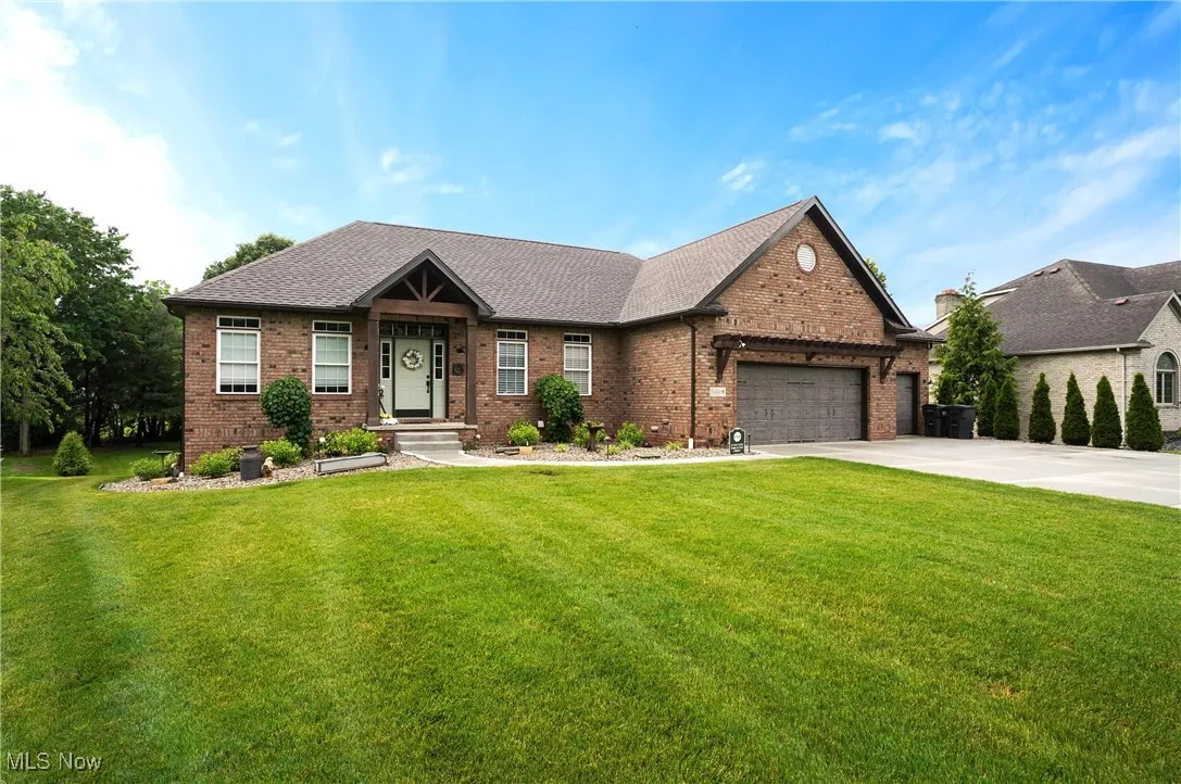 View of front of home with brick siding, an attached garage, and a front yard