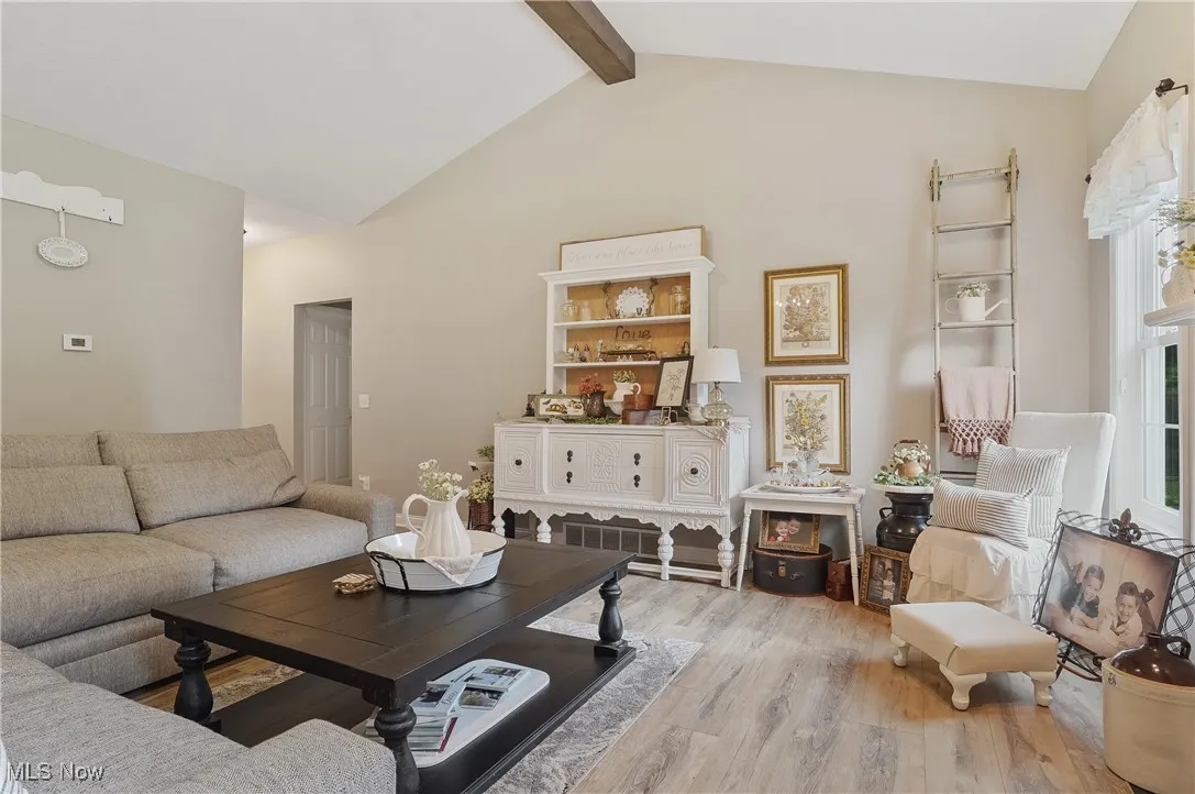 Living area featuring light wood-type flooring, beam ceiling, and high vaulted ceiling