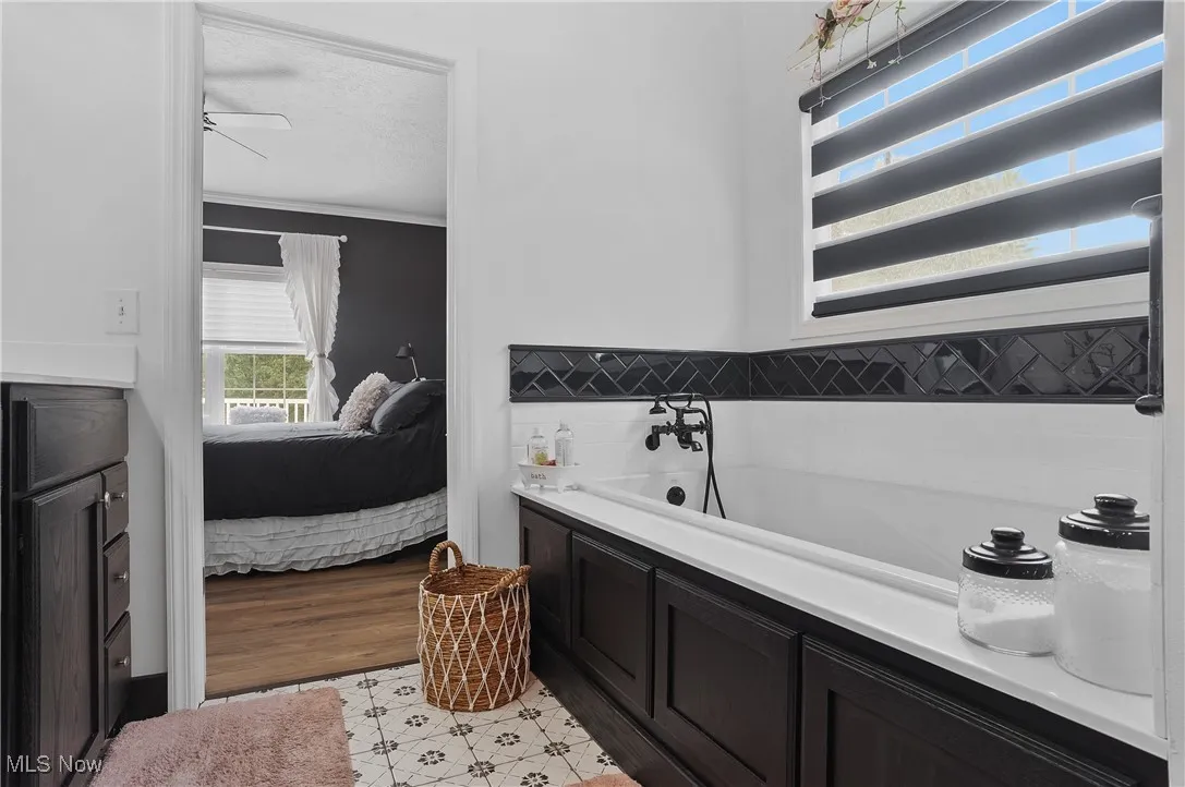 Ensuite bathroom with a garden tub, ornamental molding, a textured ceiling, and a ceiling fan