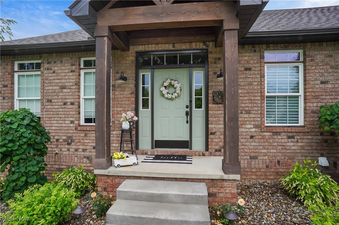 Doorway to property featuring a shingled roof and brick siding