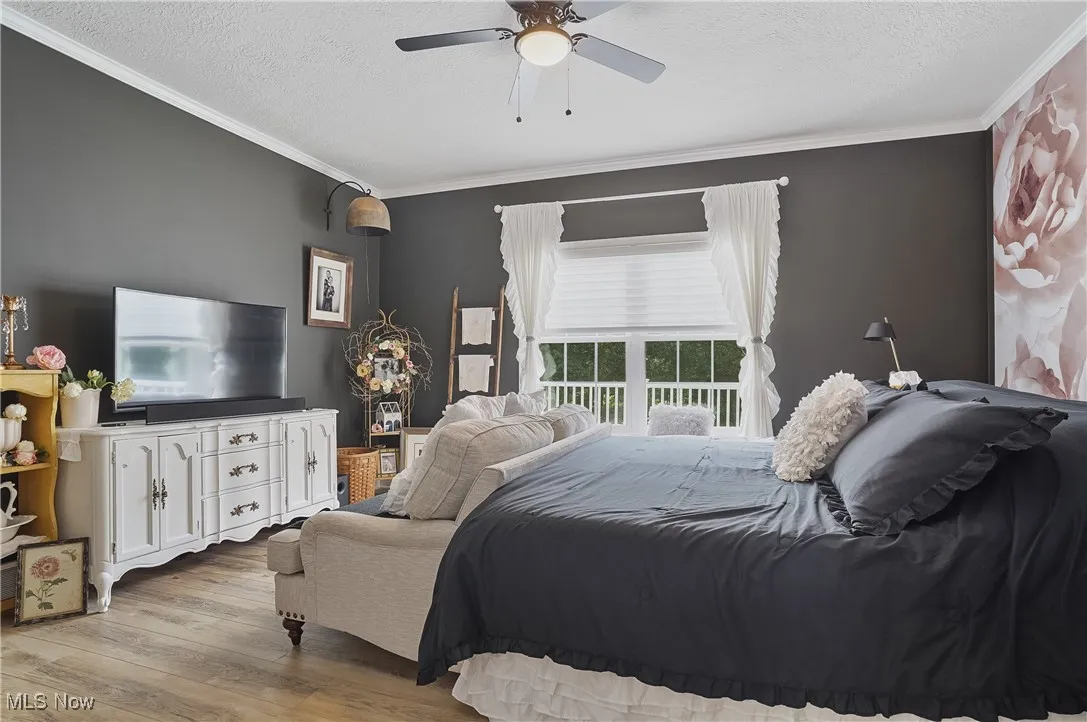 Bedroom with crown molding, wood finished floors, a textured ceiling, and ceiling fan