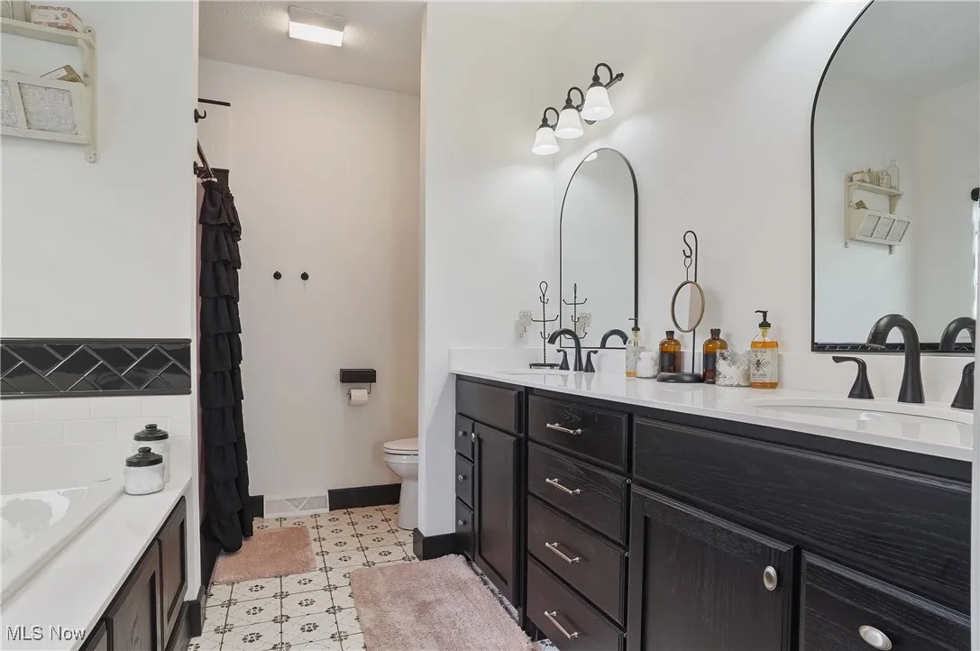 Full bath with double vanity, a tub to relax in, and curtained shower