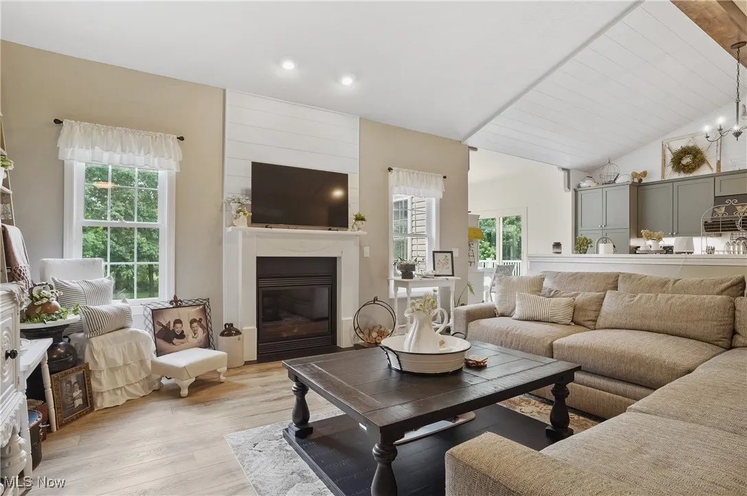 Living area with plenty of natural light, light wood-type flooring, a large fireplace, recessed lighting, and high vaulted ceiling