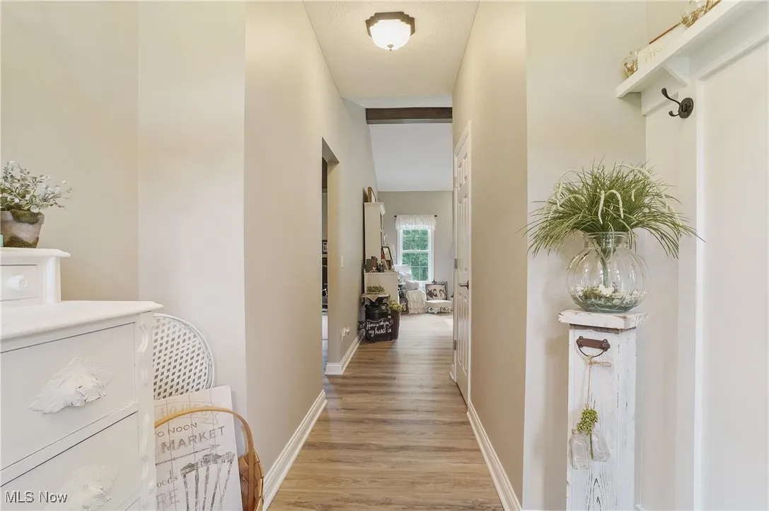 Corridor with light wood-type flooring and baseboards