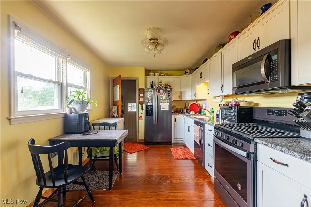 Kitchen featuring stainless steel appliances, dark wood-style flooring, and white cabinets