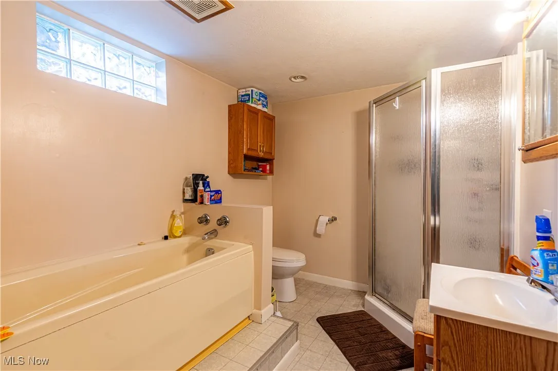 Full bath featuring a stall shower, vanity, a garden tub, and tile patterned floors