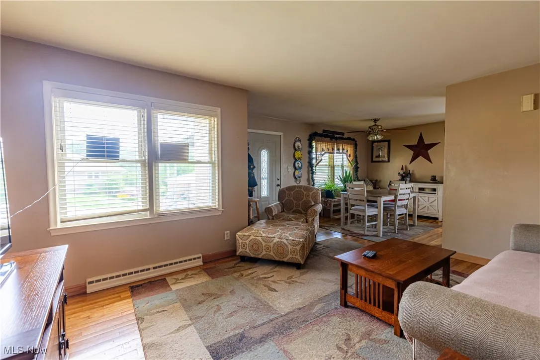Living area with a baseboard radiator, plenty of natural light, and wood finished floors