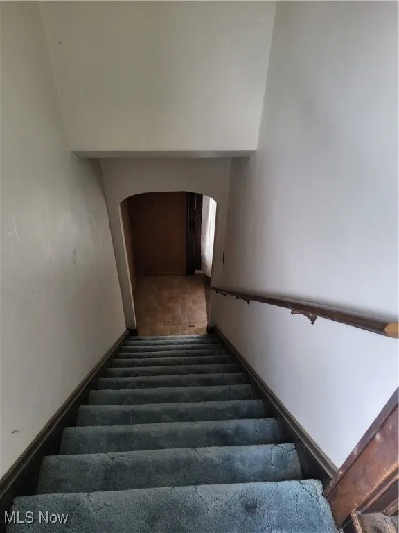Stairway featuring arched walkways and baseboards