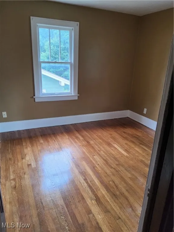 Empty room with healthy amount of natural light and hardwood / wood-style floors
