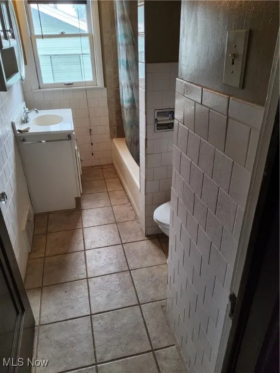 Full bath featuring tile walls, vanity, and shower / tub combo