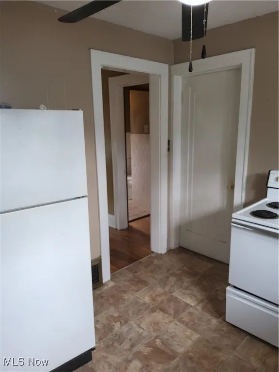 Kitchen with fridge, stove, and a ceiling fan
