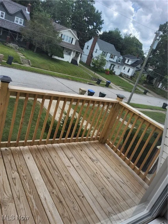 Wooden terrace featuring a residential view and a yard