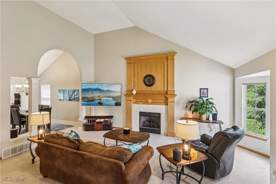 Great room featuring a vaulted ceiling, fireplace and carpet flooring