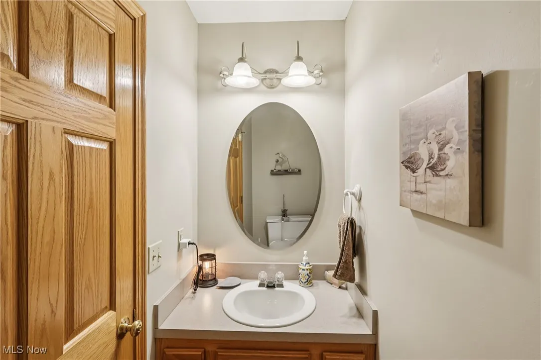 Half bath with sink, vanity, special lighting and commode