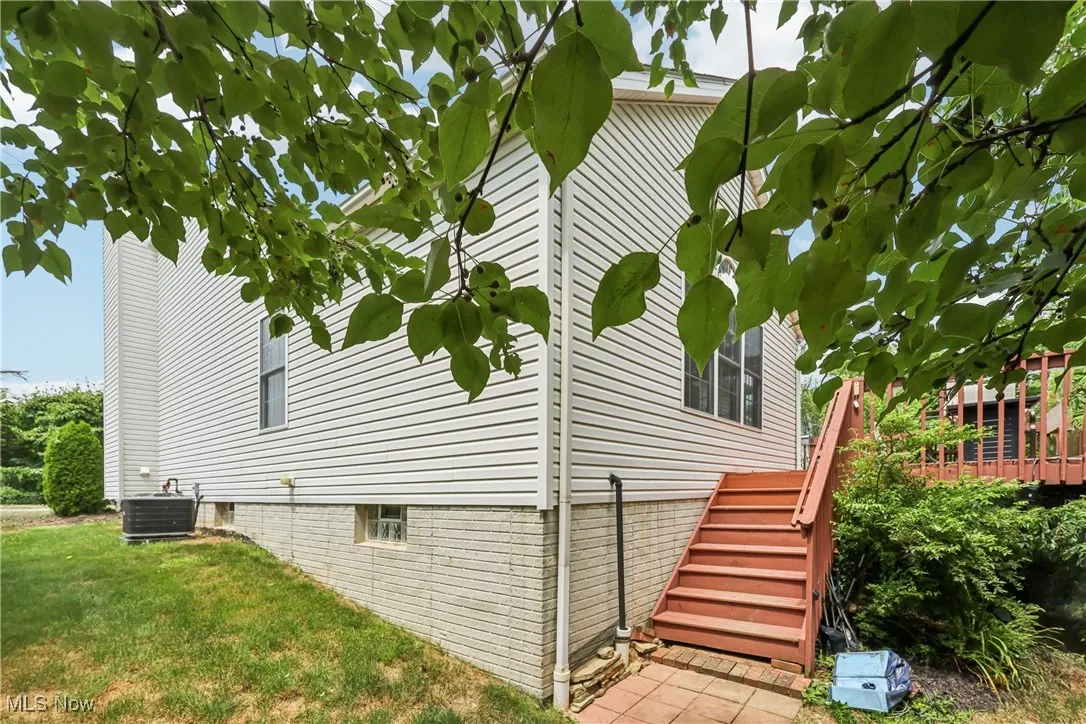 View of side of property with stairway, crawl space, and a lawn