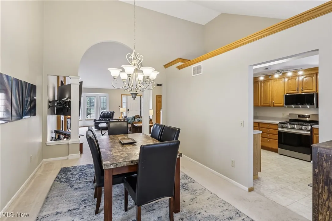 Dining room with high vaulted ceiling, arched walkways, chandelier and carpet flooring