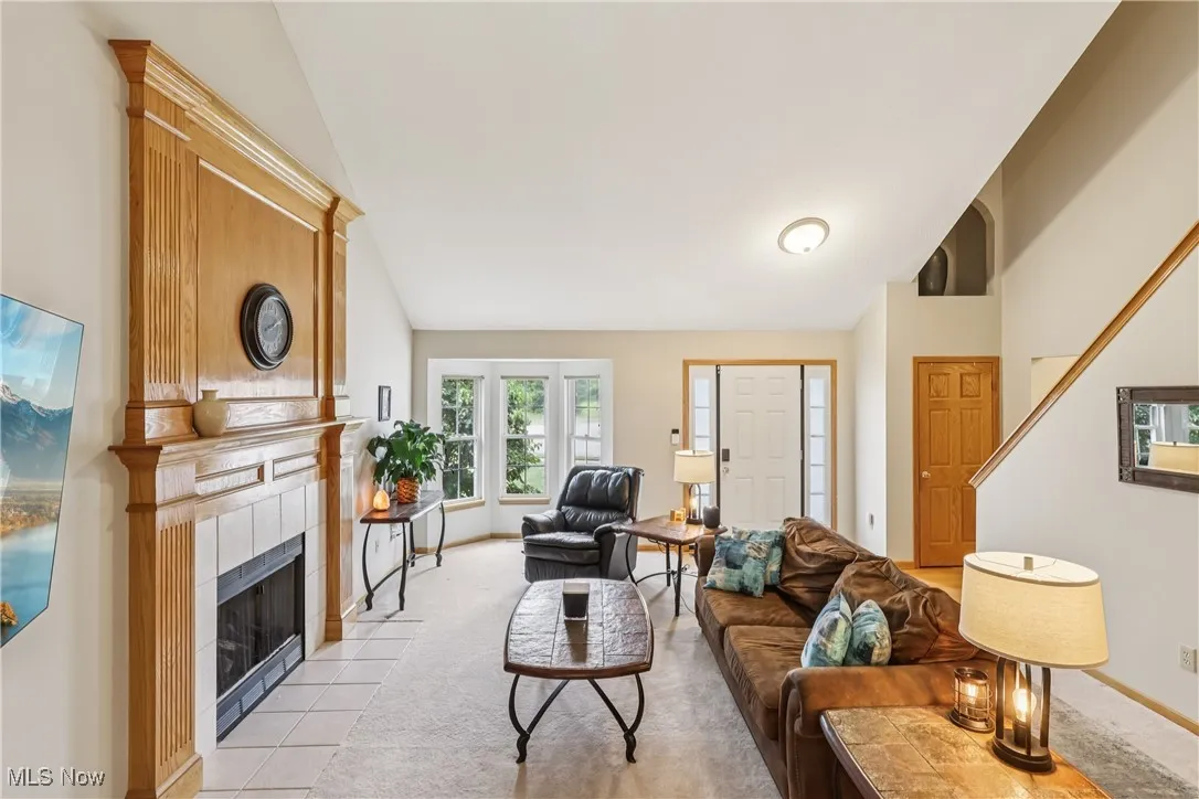 Great room featuring vaulted ceiling, a tile fireplace, and carpet flooring