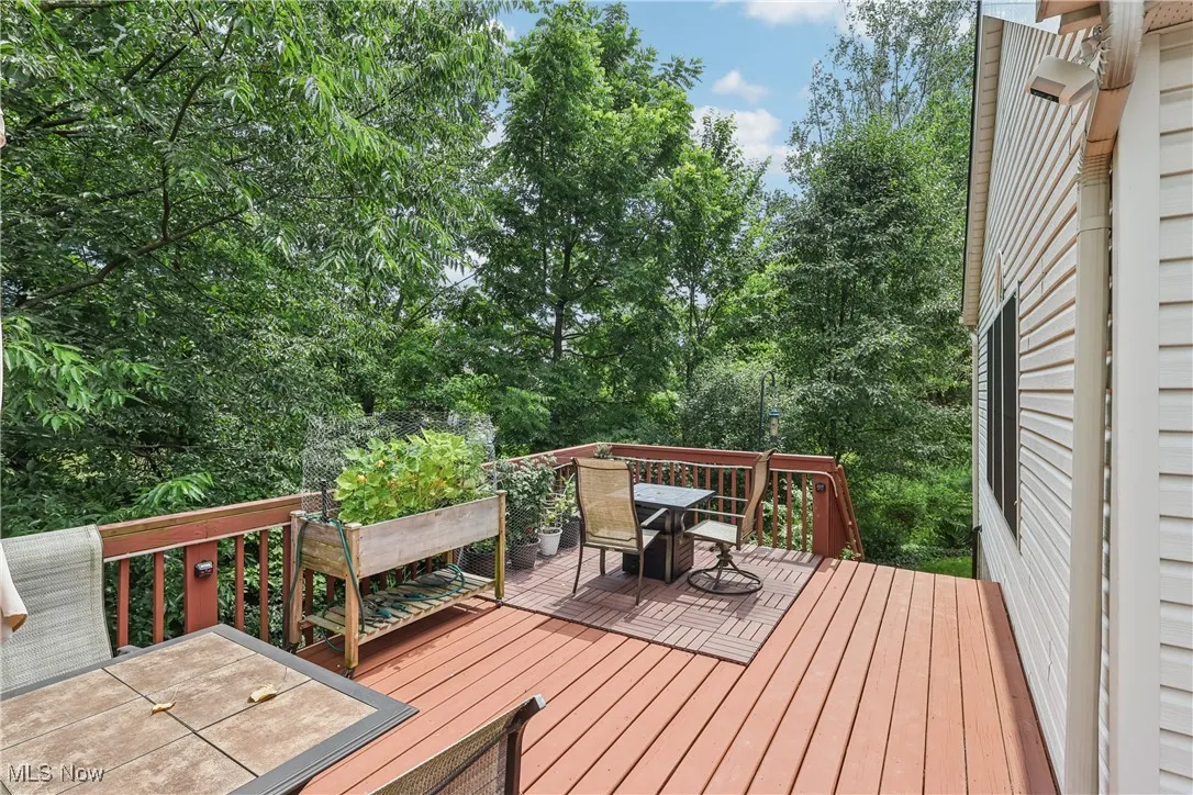 Wooden deck featuring outdoor dining space and view of wooded area