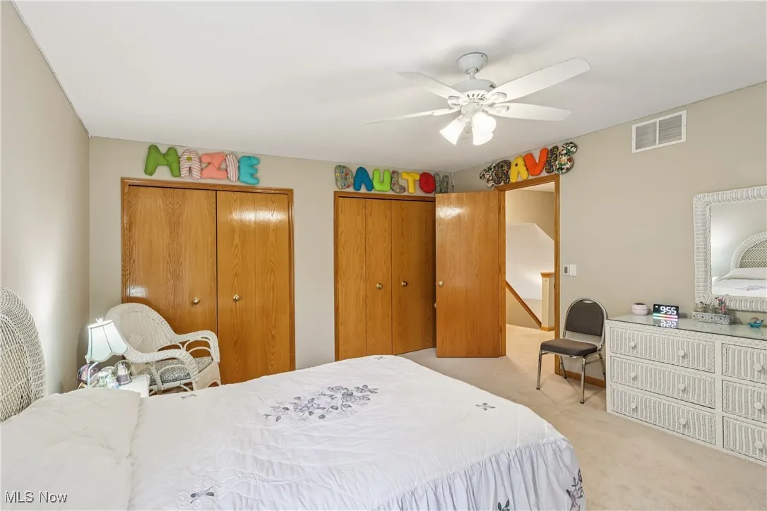 Another view of the bedroom with double closets, ceiling / fan light and carpet flooring