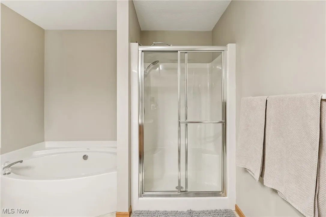 Primary bathroom with a stall shower and a jetted tub