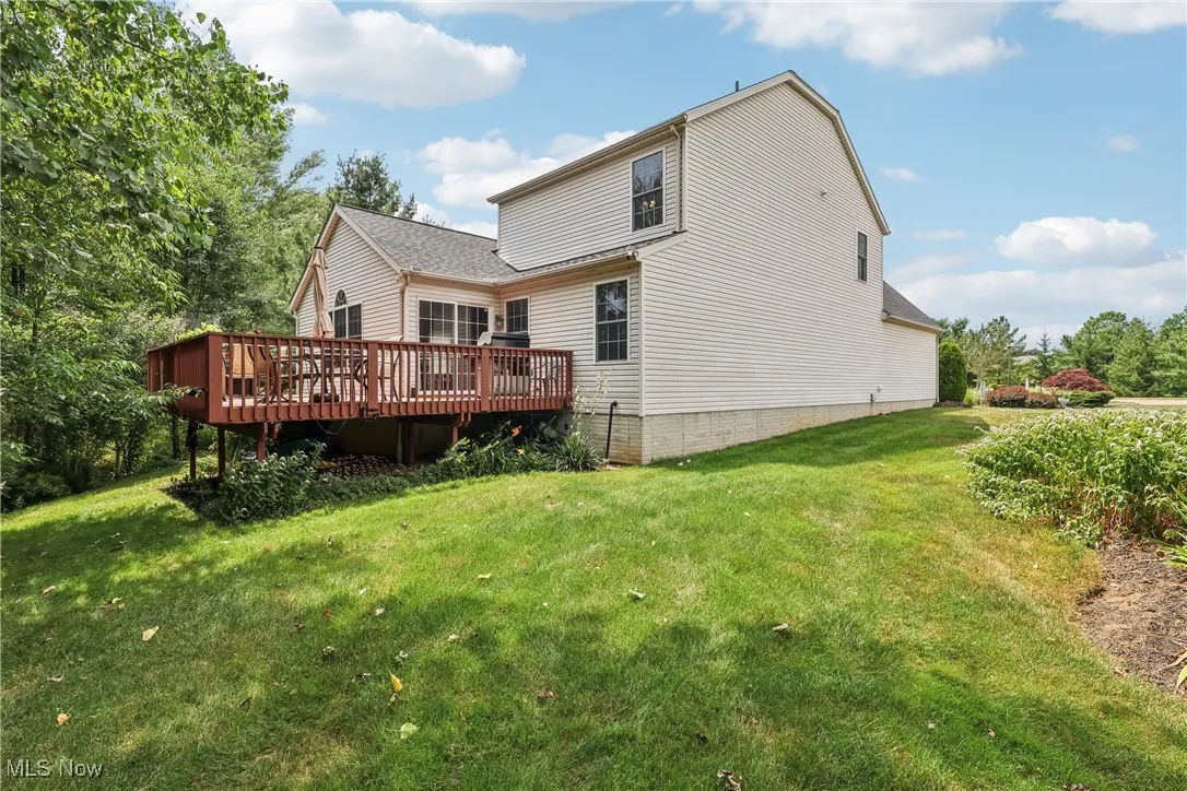 Rear view of house with a deck and a lawn