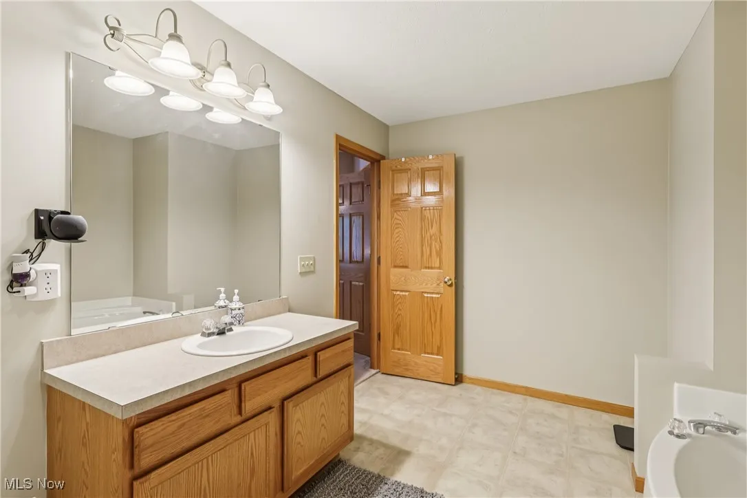 Primary bathroom with sink, vanity special lighting, jetted tub and tile flooring