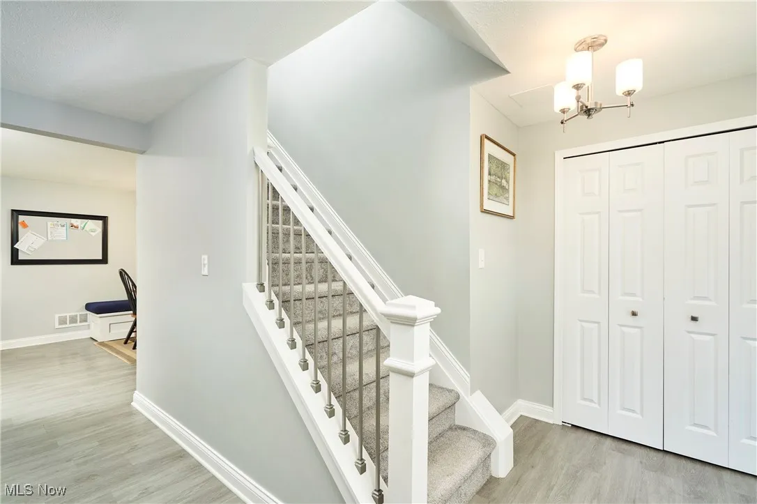 Stairs with wood finished floors and a chandelier