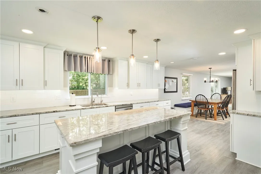 Kitchen featuring white cabinetry, recessed lighting, a kitchen bar, and light wood-style floors