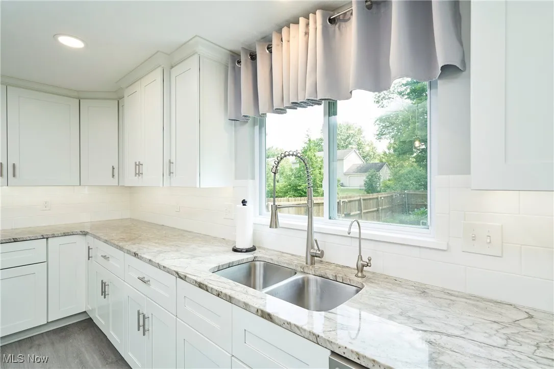 Kitchen with white cabinetry, backsplash, light stone counters, wood finished floors, and recessed lighting