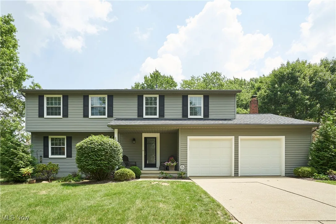 Traditional home featuring a front lawn, driveway, covered porch, and a chimney