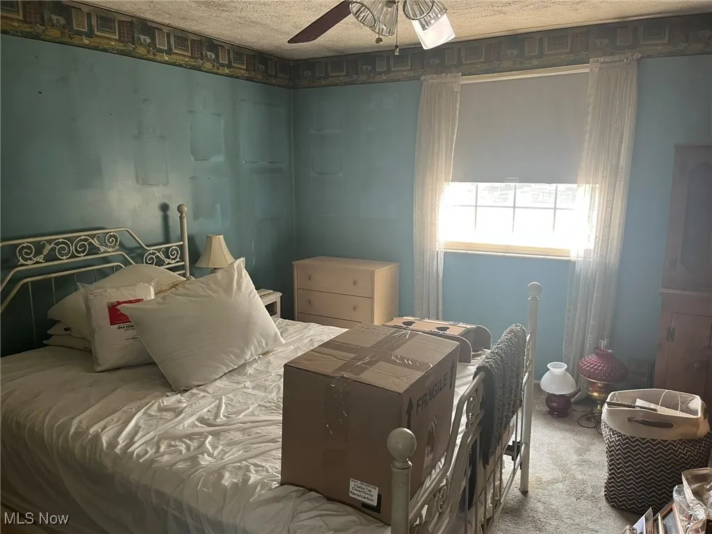 Carpeted bedroom featuring a textured ceiling and ceiling fan